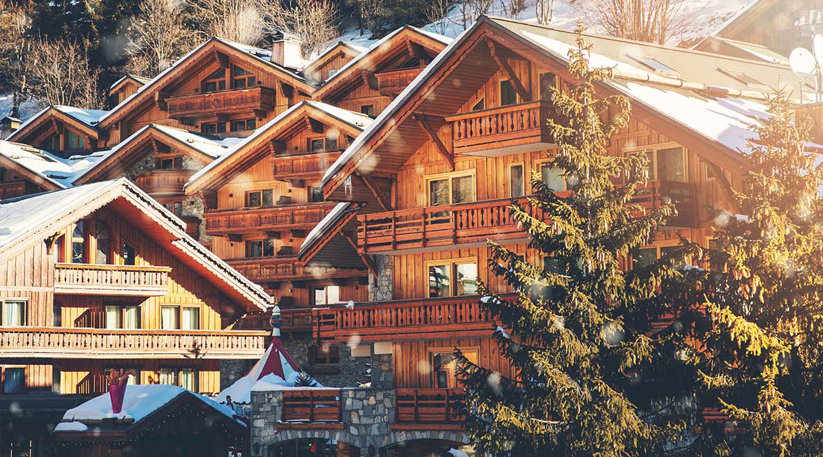 wooden chalets in the alp mountains France surrounded by snowy hills and fir trees